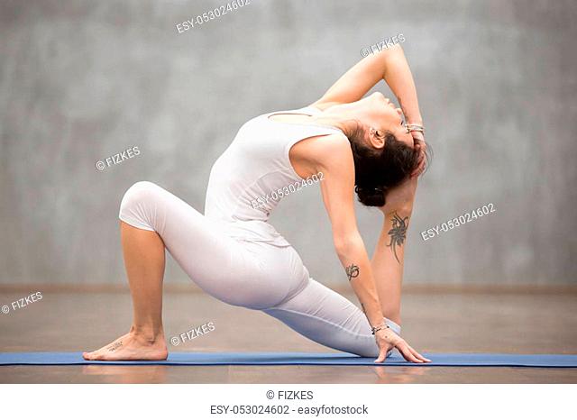 Side view portrait of beautiful young woman with tattoo on her foot meaning Wild kitty working out in fitness club or at home, doing yoga, pilates exercise