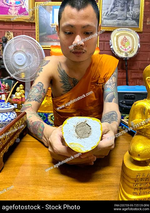 23 June 2020, Thailand, -: Phra Anuchit Upanan, a monk in the Wat Samngam temple, shows the inside of a Kuman Thong, a baby figure which is supposed to contain...