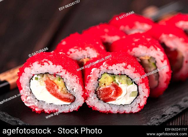 California sushi roll with crab, avocado, cucumber and tobiko caviar served on black board - Japanese food