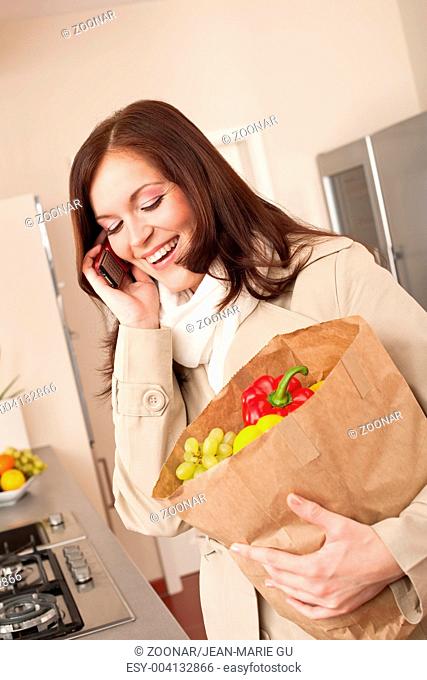 Smiling woman with mobile phone holding shopping bag