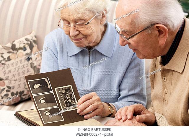 Senior couple watching old photograph album at home