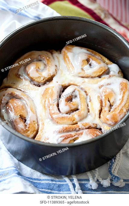 Cinnamon buns with pecan nuts and butter glaze in a baking tin