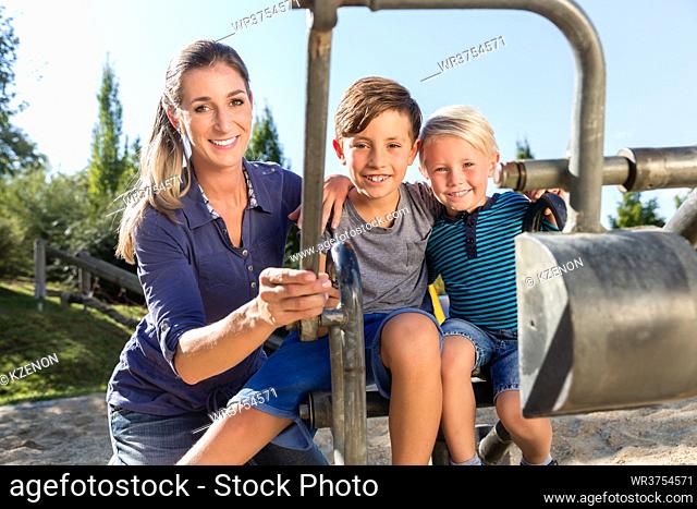 Two brothers playing together at toy excavator on playground
