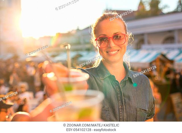 Beautiful young girl toasting outdoors on Open kitchen street food festival in Ljubljana, Slovenia. Popular summer urban tourist event in capital