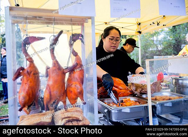 29 October 2023, Berlin: Tipa Pitibut, chef, prepares a dish of grilled end and crispy pork belly at the Thai Market in Prussia Park