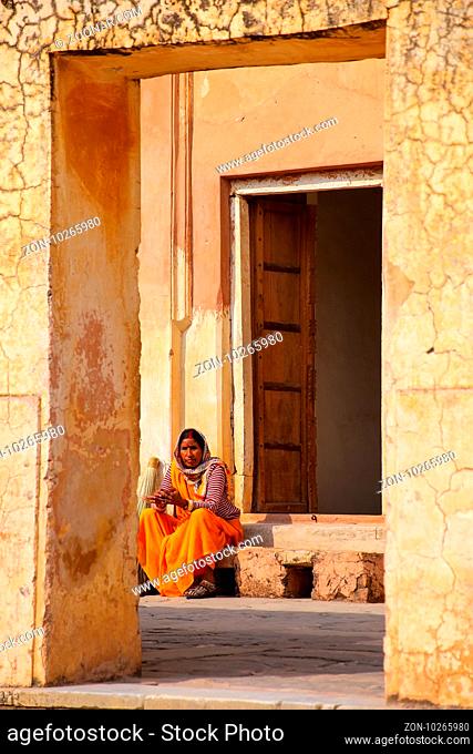 Local woman sitting in the fourth courtyard of Amber Fort, Rajasthan, India. Amber Fort is the main tourist attraction in the Jaipur area
