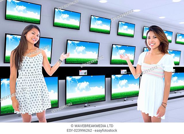 Two pretty asian women presenting against televisions for sale