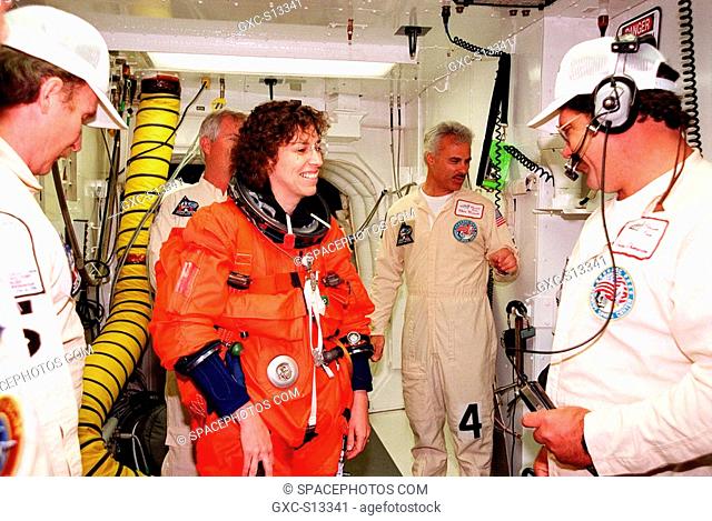 04/29/1999 --- In the white room, an environmental chamber at Launch Pad 39B, Mission Specialist Ellen Ochoa Ph.D. gets help with her equipment from Al Schmidt