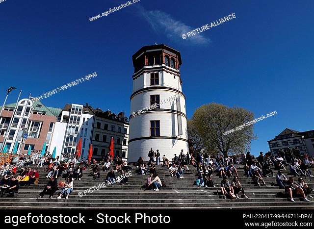 17 April 2022, North Rhine-Westphalia, Duesseldorf: In Düsseldorf, people sit on the Burgplatz on the Rhine bank promenade in the best Easter Sunday weather
