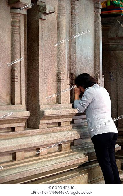 Mariamman hindu temple. Worshipper praying on the wall of the sanctuary