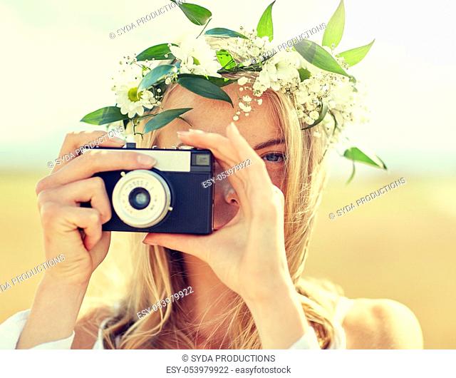 happy woman with film camera in wreath of flowers