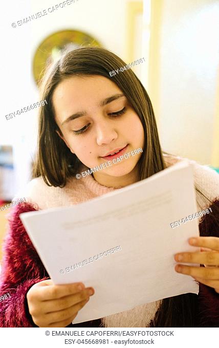 little girl, teen ager reads the papers she holds in her hand, studies for questioning school-close-up