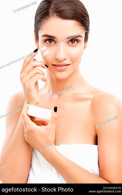 Beauty Youth Skin Care Concept - Close up Beautiful Caucasian Woman Face Portrait applying some cream to her face. Beautiful Spa model Girl with Perfect Fresh...