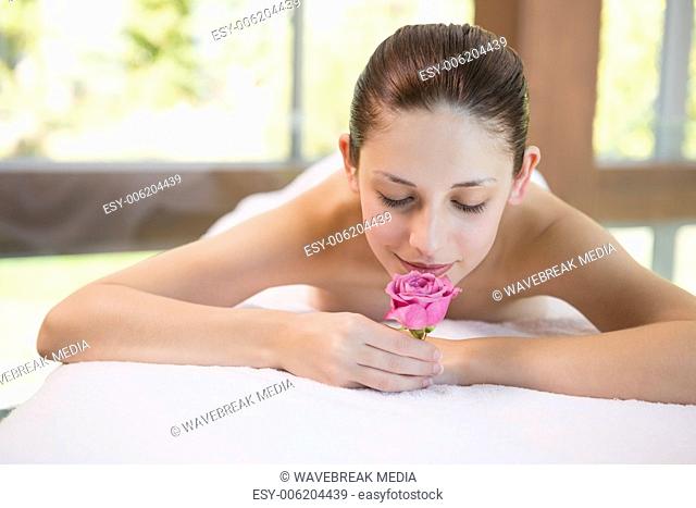 Beautiful woman holding flower on massage table at spa center