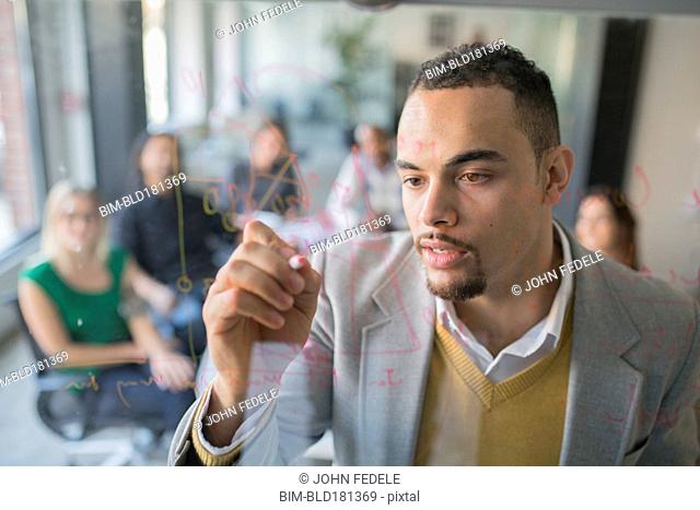 Businessman drawing graph on glass wall in office