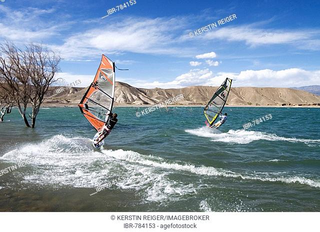 Two windsurfers sailing at high speed across the windswept dam at Cuesta del Viento, Rodeo, San Juan Province, Argentina, South America