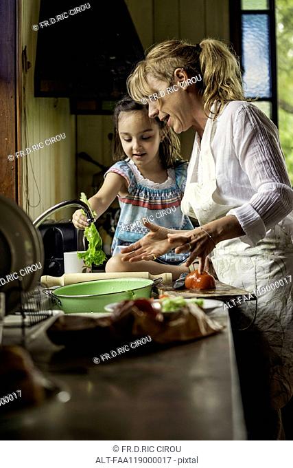 Mature woman teaching her granddaughter in kitchen