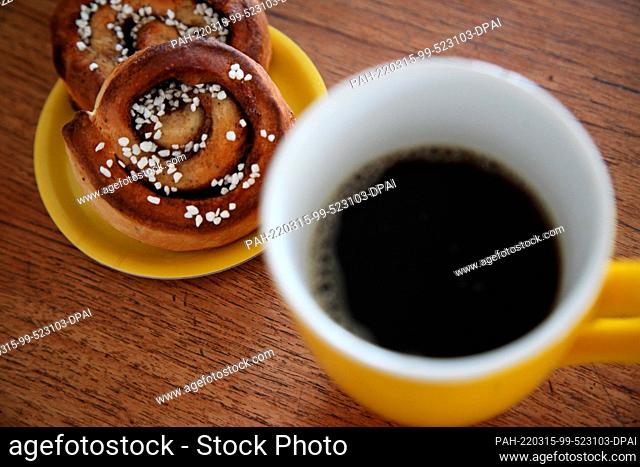 ILLUSTRATION - 14 March 2022, Denmark, Kopenhagen: Two cinnamon buns lie next to a coffee mug. A secret ingredient of Swedish happiness is found in the daily...