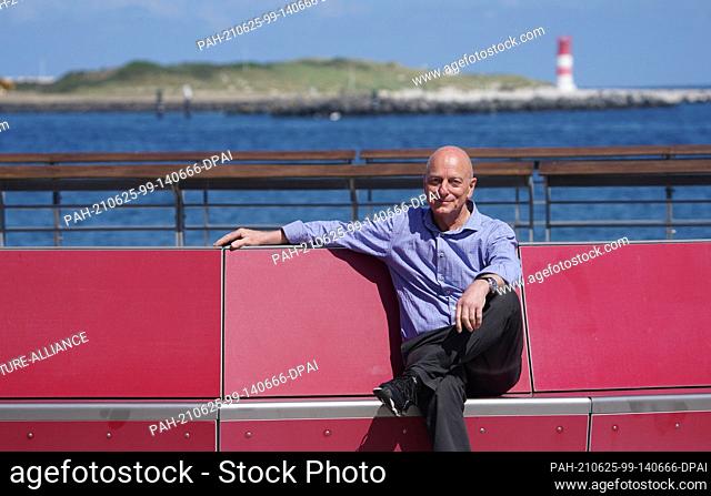 15 June 2021, Schleswig-Holstein, Helgoland: Stephan Hauke, the new tourism director of the high seas island Helgoland, sits on a bench at the landing stages of...