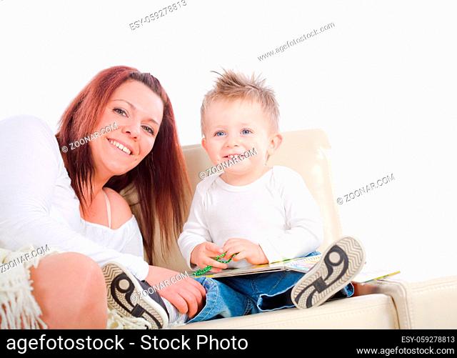 Happy family sitting on sofa at home mother reading for baby boy from story book