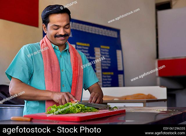 Portrait of a Man chopping capsicum with knife in restaurant