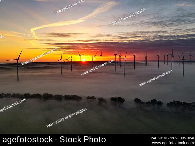 17 October 2023, Brandenburg, Petersdorf: Sunrise in the morning fog over the wind energy park ""Odervorland"" (aerial photo with a drone)