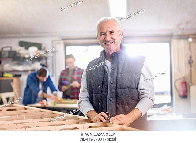 Portrait smiling male carpenter working on wood boat in workshop