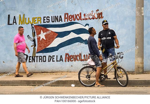 A wall on the roadside in Cienfuegos is painted with the Cuban national flag and a revolutionary slogan. (26 November 2017) | usage worldwide