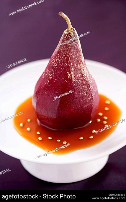 Poached pear sprinkled with gold dust in caramel sauce