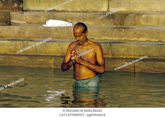 Steps by water. Ghats. Sacred river Ganges. Man in water up to waist. Praying. Hindu