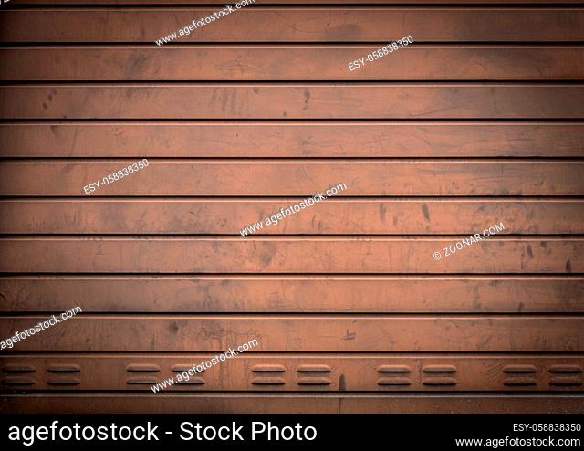 Weathered metallic roll up door. Rusty iron gate with nice lighting and elegant vignetting to draw the attention. Urban industrial style