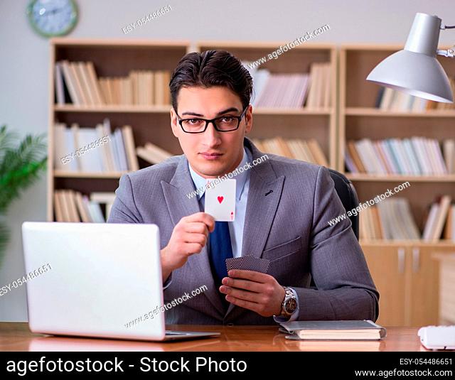 The businessman gambling playing cards at work