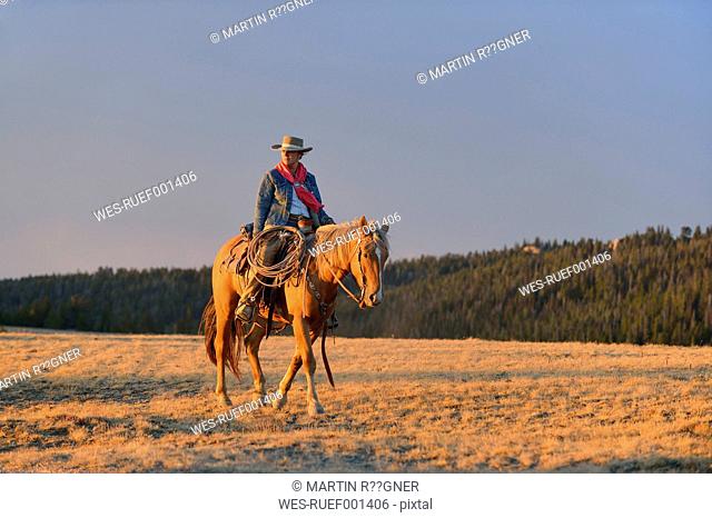 USA, Wyoming, cowgirl riding at evening light