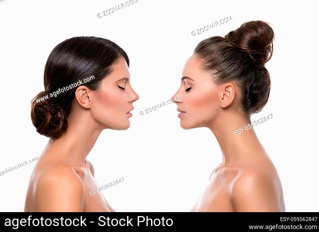 Two beautiful young women with perfect skin. Isolated over white background. Profiles. Beauty shot. Copy space