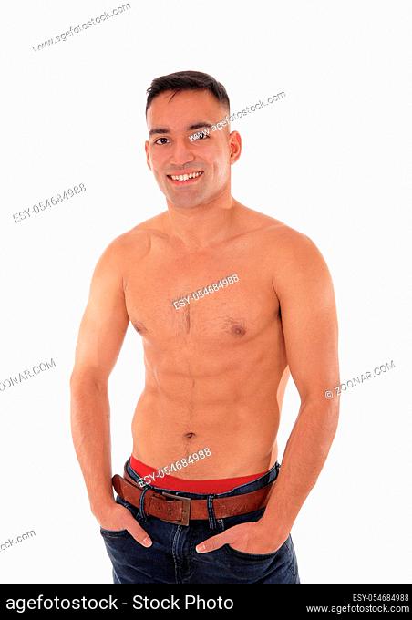 A handsome young east Indian man standing shirtless and smiling in jeans with red underwear showing, isolated for white background