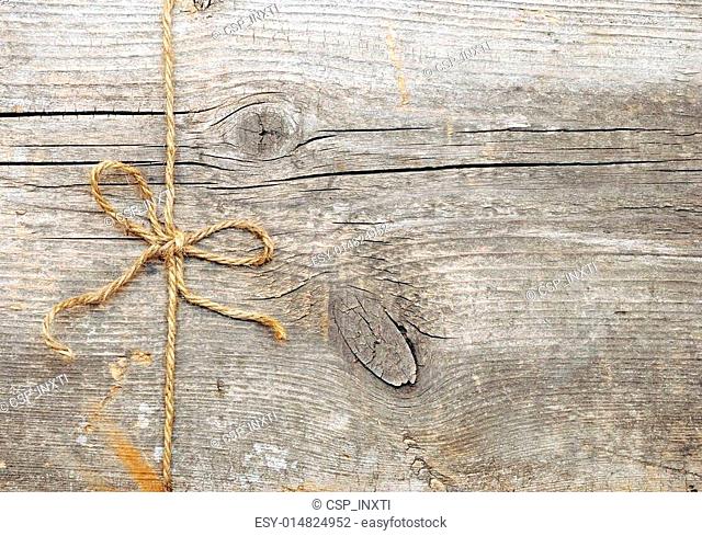 String tied in a bow, over old wood