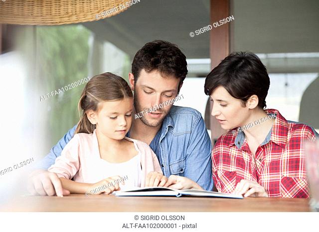 Little girl reading with her parents