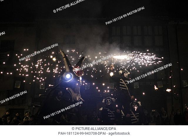 23 November 2018, Spain, Salvatierra: A man disguised as a devil (l) dances with ""skeletons"" in the middle of a ""firecracker inferno"" in the small town of...