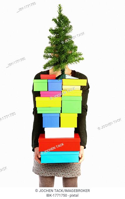 Woman carrying cardboard boxes with gifts and a small Christmas tree