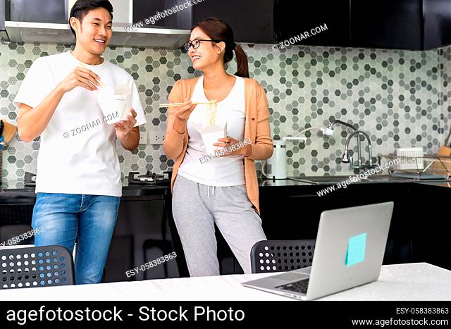Asian couple work from home in the kitchen with delivery take away food while city lockdown from coronavirus covid-19 pandemic