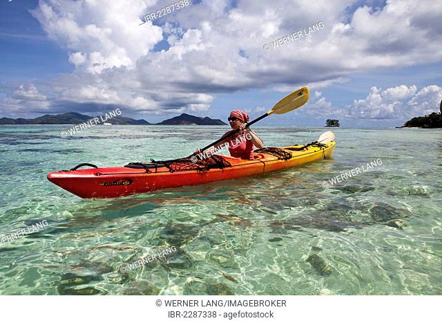 Woman, 40 years, in kayak, Island of Praslin at back, La Digue, Seychelles, Africa, Indian Ocean