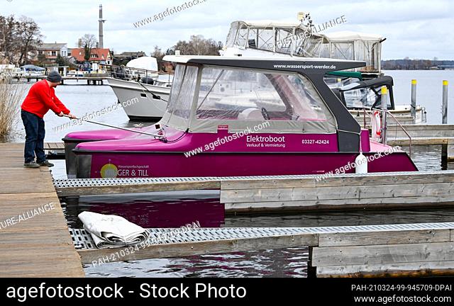 23 March 2021, Brandenburg, Werder (Havel): Kai Grunow from the water sports shop Krüger and Till secures an electric boat in the harbour of Werder