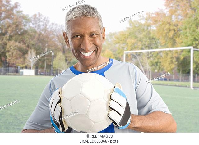 Mixed race man in soccer uniform holding ball