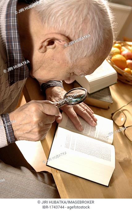 Old man, senior, 92 years, with book and magnifying glass