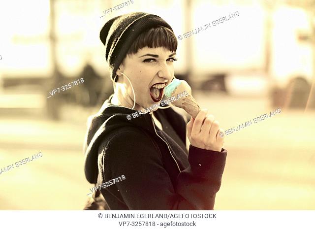 vibrant woman using ice cream cone as microphone, screaming loud her opinion, during warm winter day, in city Cottbus, Brandenburg, Germany