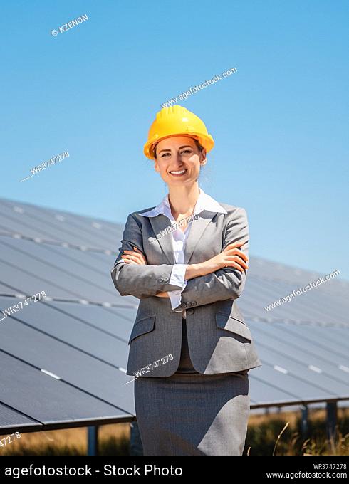 Woman investor in clean energy standing proudly in front of solar panels