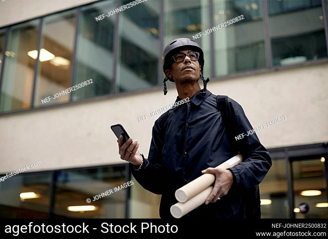 Bicycle courier using cell phone in front of office building
