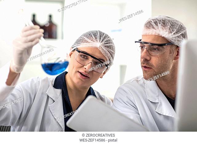 Two scientists working in lab together looking at flask