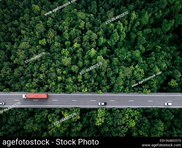 Aerial top view of car and truck driving on highway road in green forest. Sustainable transport. Drone view of hydrogen energy truck and electric vehicle...