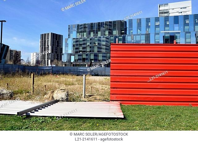 Fallen red aluminium wall, green grass, wasteland, fence, office buildings, blue sky. Plaça Europa, Plaza Europa, District VII, Gran Via